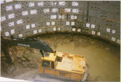 Digging away at the base, as the spoil was removed hydraulic rams pushed down on the ring forcing the complete ring downwards, as more concrete rings were added the weight alone did most of the work.